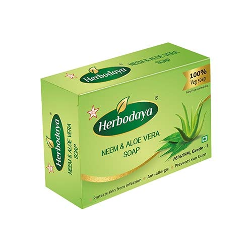 Herbodaya Neem & Aloe Vera Soap bar on a wooden surface with green leaves, showcasing natural ingredients.