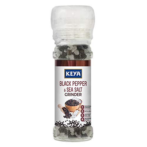 Keya Black Pepper & Sea Salt Grinder, 80g, with twist top, standing next to fresh black peppercorns and sea salt. - Image 2