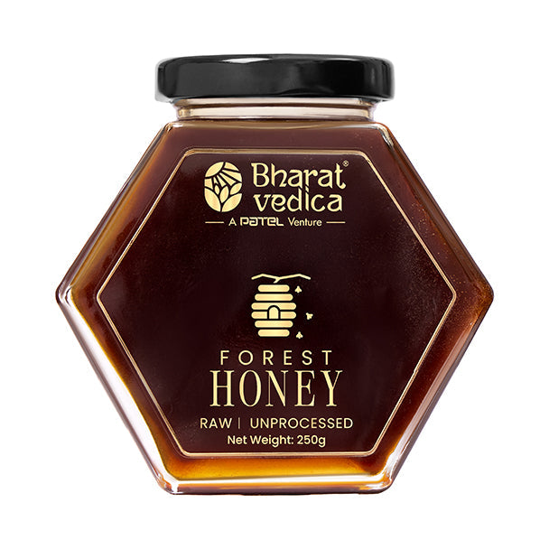 Bharat Vedica Forest Honey in a signature hexagon bottle, showcasing its deep amber color on a natural background.